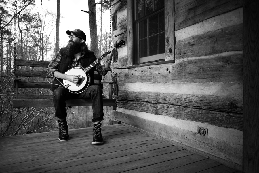 Crowder on a cabin porch with a banjo