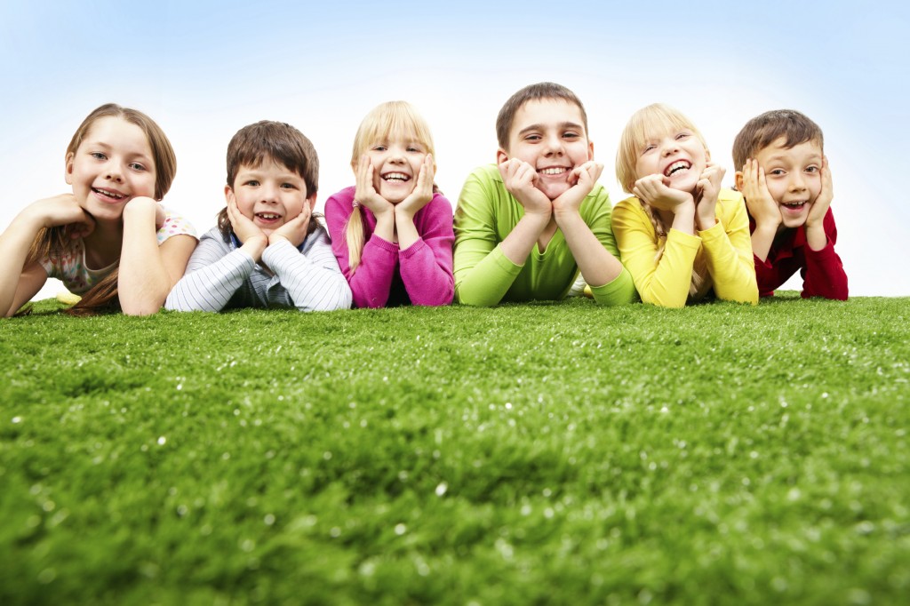 Image of happy boys and girls lying on a green grass