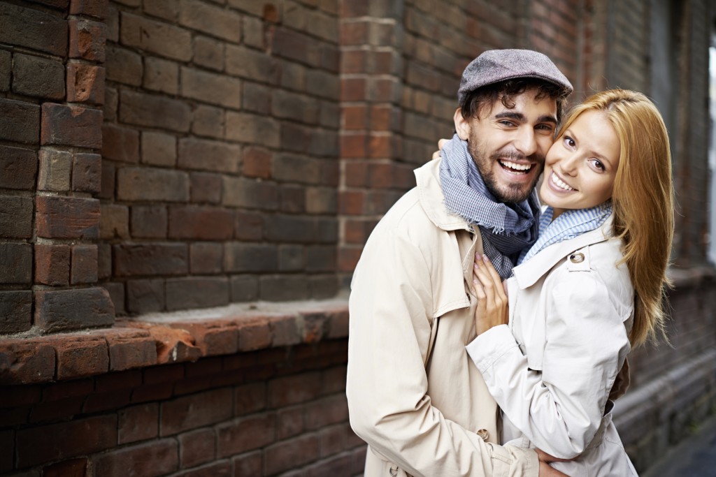 Portrait of affectionate couple in stylish clothes looking at camera outside