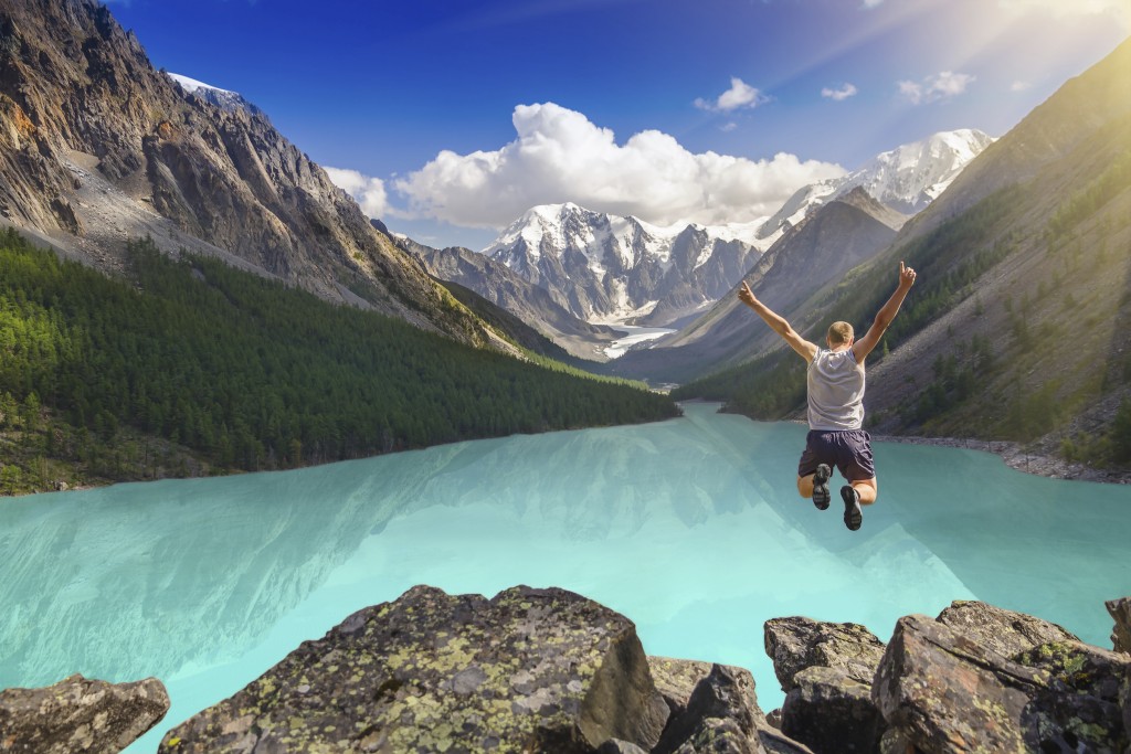 Beautiful mountain landscape with lake and jumping man