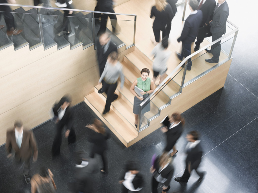 Businessman leaning on busy office staircase