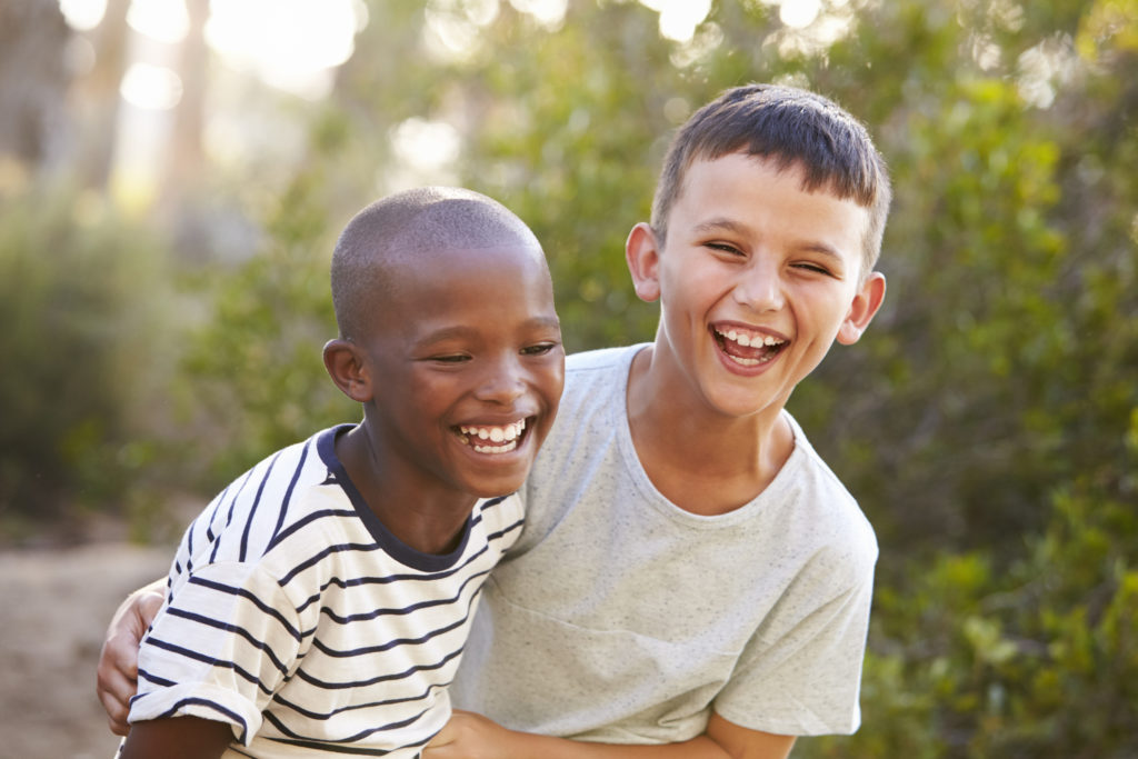 Portrait of two boys embracing and laughing hard outdoors